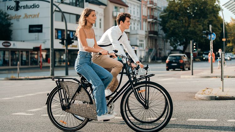  Frau und Mann fahren nebeneinander Rad in der Stadt, es ist Sommer