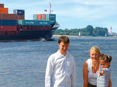  Familienausflug an die Elbe, im Hintergrund: Containerschiff, Windräder Segelboote und ein Leuchtturm