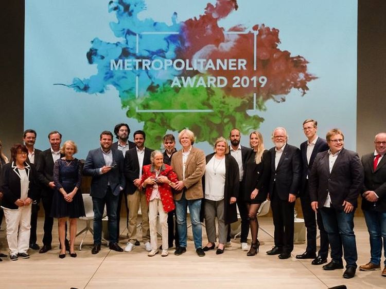  Auf einer Bühne stehen in einer Reihe die Gewinner und Förderer des Metropolitaner Awards 2019.