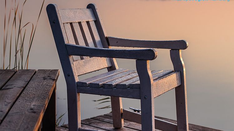  Das Teaserbild des Podcasts zeigt einen Holzstuhl auf einem Steg am See bei Sonnenuntergang.