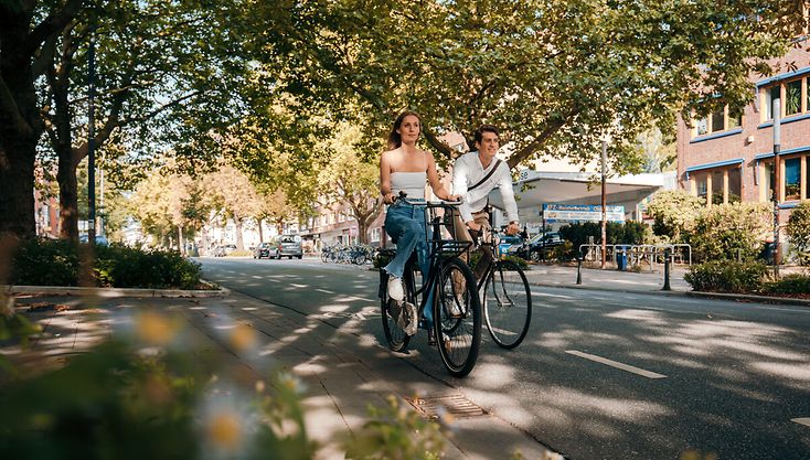 Frau und Mann fahren nebeneinander Rad in der Stadt, es ist Sommer