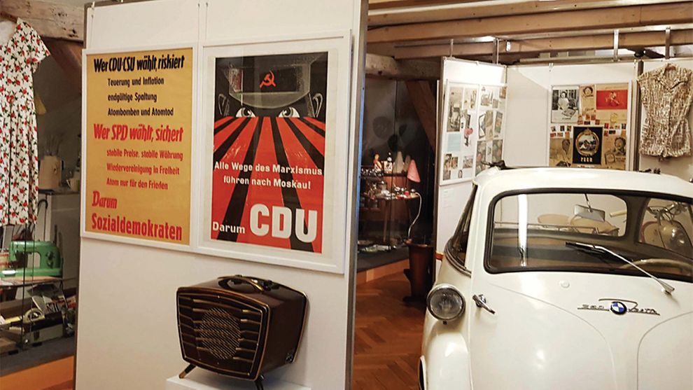 Plakate und ein Auto in einem Ausstellungsraum