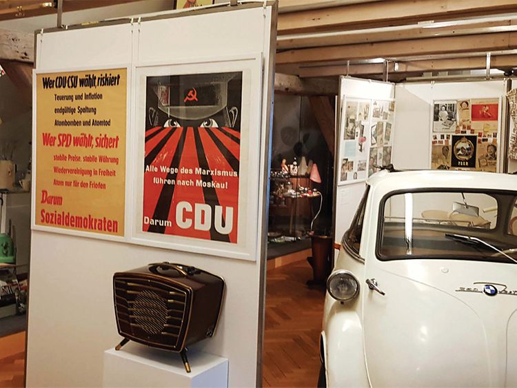  Plakate und ein Auto in einem Ausstellungsraum
