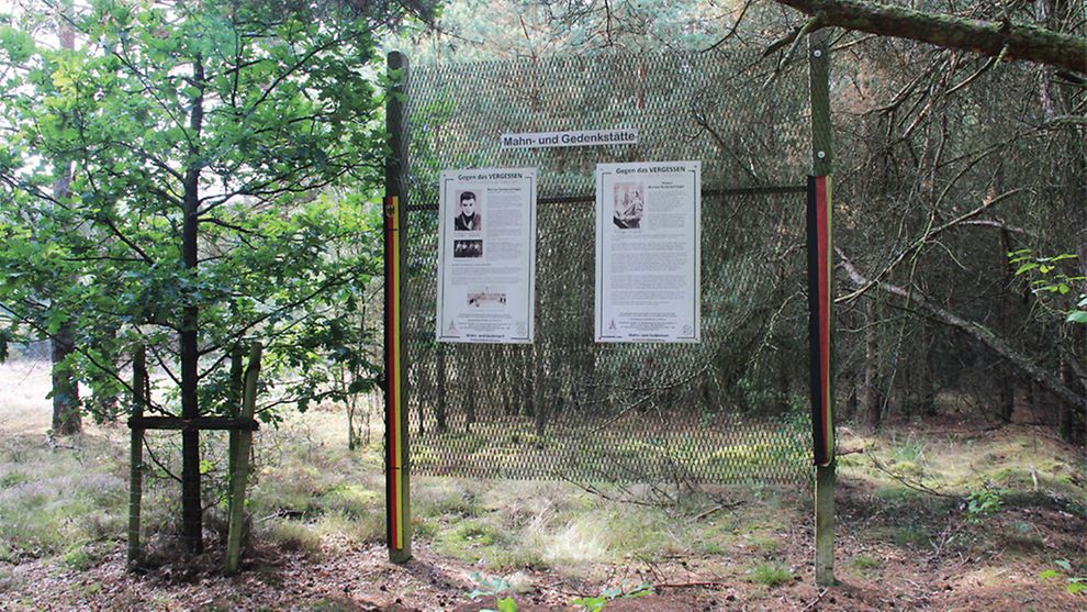 Zaun mit Gedenktafeln in einem Wald 