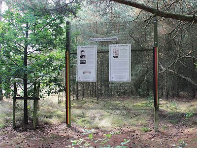  Zaun mit Gedenktafeln in einem Wald 