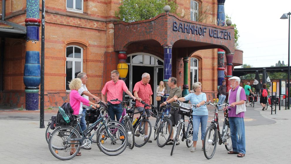 A group of cyclists in front of the Uelzen Hundertwasser train station