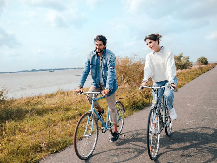  A young couple of cyclists with wide river in background
