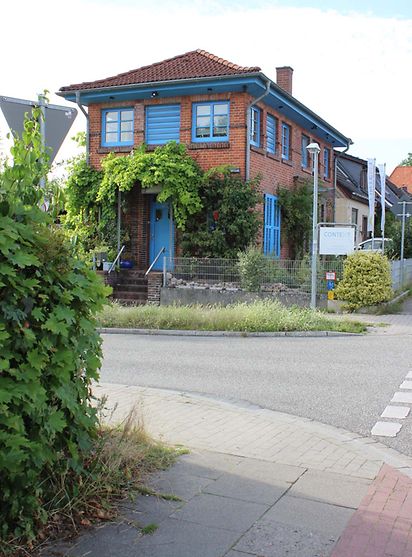 Ein Haus mit blauen Fensterrahmen und Türen steht an einer Kreuzung.