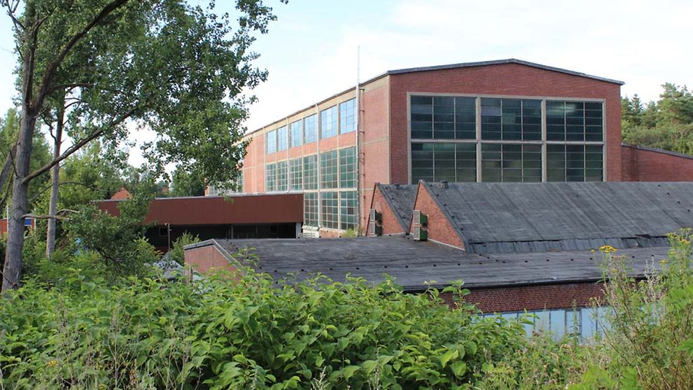 Die ehemalige Hauptwerkstatt Dynamitfabrik ist ein großes Gebäude mit großen Glasfenstern.