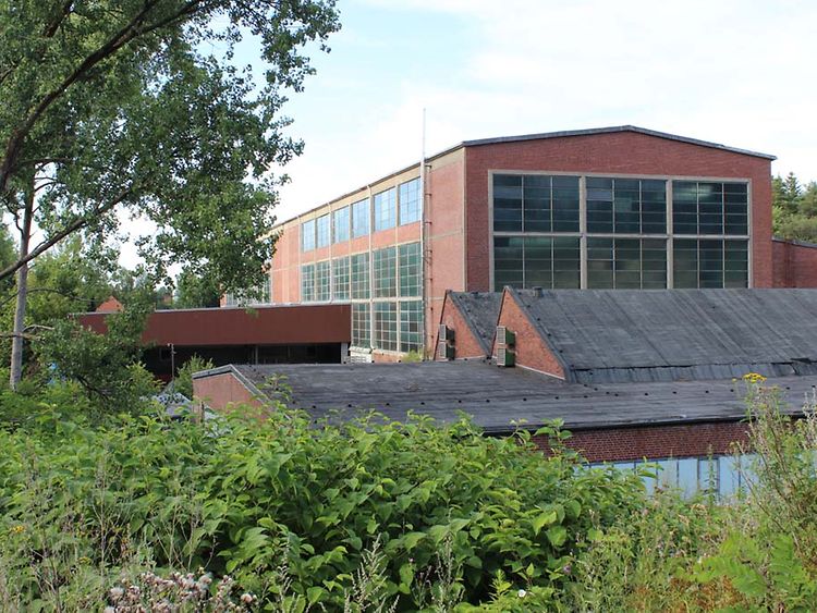  Die ehemalige Hauptwerkstatt Dynamitfabrik ist ein großes Gebäude mit großen Glasfenstern.