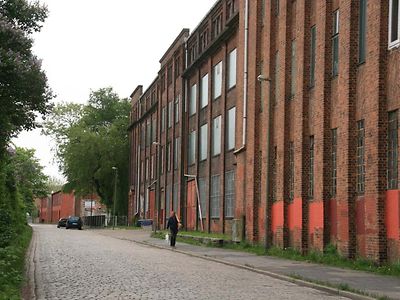  An der Seite einer Kopfsteinpflasterstraße steht ein Gebäude aus rotem Backstein.