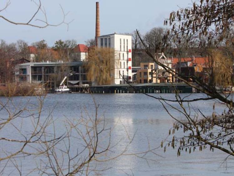  Am anderen Ende eines Gewässers ist eine Fabrikanlage zu sehen. Es ist die ehemalige Brauerei Schall & Schwencke.